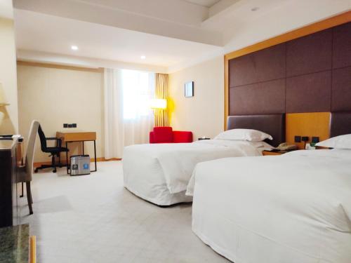 a hotel room with two beds and a desk at Aurum International Hotel Xi'an in Xi'an