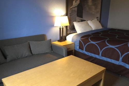 a hotel room with a couch and a bed at Super 8 by Wyndham Swift Current in Swift Current