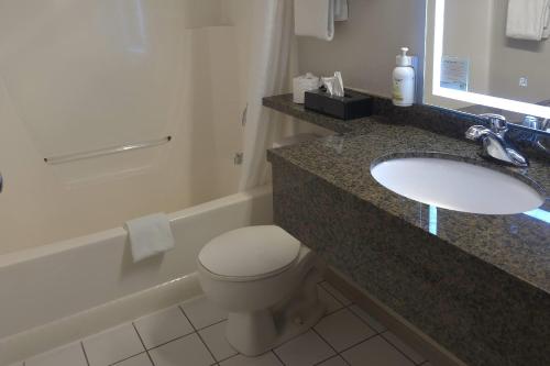 a bathroom with a sink and a toilet and a tub at Super 8 by Wyndham Swift Current in Swift Current