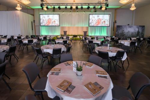 a banquet hall with tables and chairs and two projection screens at Hotell Södra Berget in Sundsvall