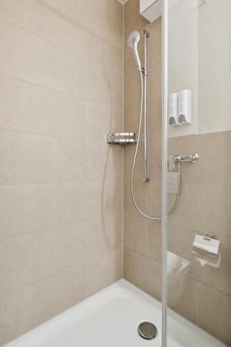 a shower with a glass door in a bathroom at UP&GREAT Apartments - Chic Urban Homes in Zürich