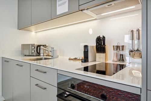 a kitchen with white cabinets and a stove at UP&GREAT Apartments - Chic Urban Homes in Zürich