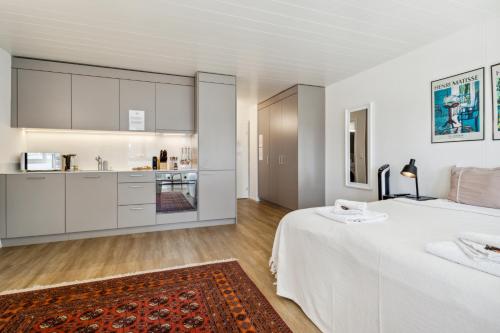 a white bedroom with a large bed and a kitchen at UP&GREAT Apartments - Chic Urban Homes in Zürich