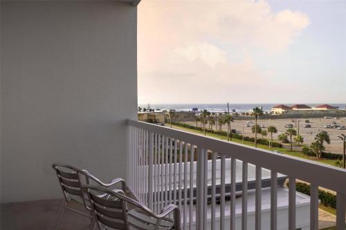 a balcony with two chairs and a view of the beach at Hampton Inn & Suites Galveston in Galveston