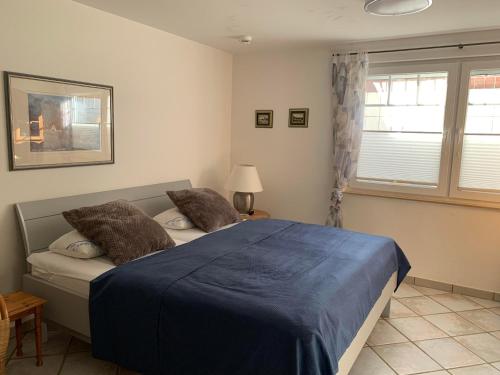 a bedroom with a bed with blue sheets and a window at Sylter Rose 3A in Süderende