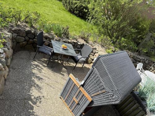 a patio with a table and chairs and a stone wall at Sylter Rose in Süderende