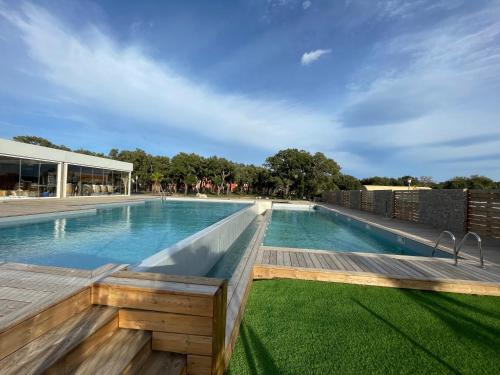 une piscine à débordement avec une terrasse en bois et un bâtiment dans l'établissement T2 Saint Cyprien proche de la mer, à Lecci