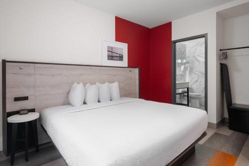 a bedroom with a white bed and a red wall at Ramada by Wyndham Brooklyn Near Flatbush in Brooklyn