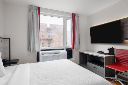 a hotel room with a bed and a desk and a television at Ramada by Wyndham Brooklyn Near Flatbush in Brooklyn