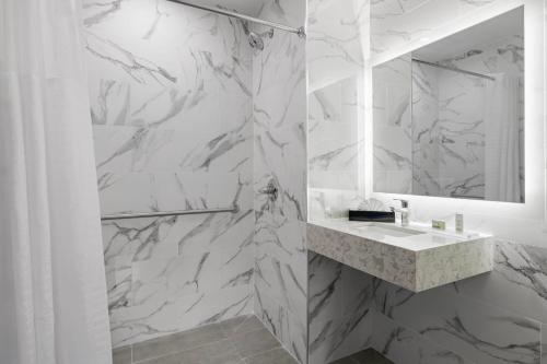a white marble bathroom with a sink and a mirror at Ramada by Wyndham Brooklyn Near Flatbush in Brooklyn