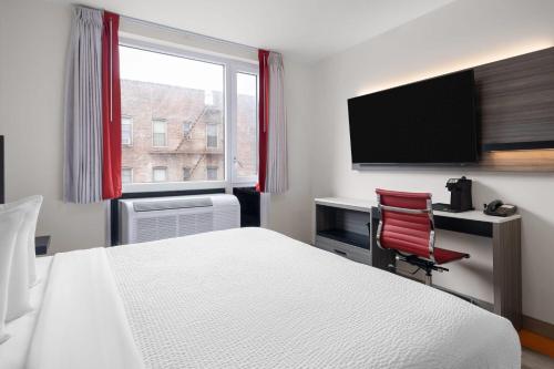 a hotel room with a bed and a desk and a television at Ramada by Wyndham Brooklyn Near Flatbush in Brooklyn