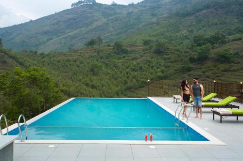 a man and a woman standing next to a swimming pool at Koviloor Resort in Vattavada