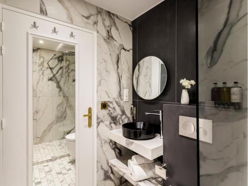 La salle de bains est pourvue de murs en marbre noir et blanc. dans l'établissement Merveil - Luxury Suite - Louvre - Aboukir IX, à Paris