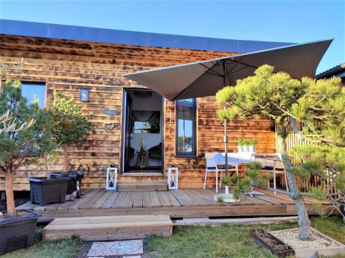 a wooden deck with a table and an umbrella at Tinyhouses am Neusiedlersee in Fertőrákos