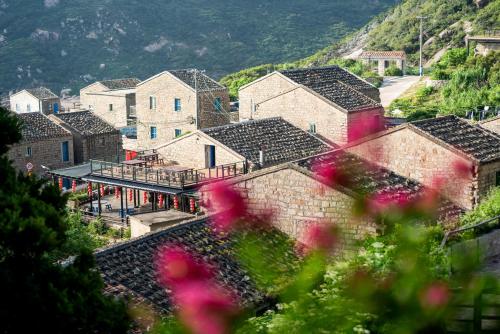 a group of buildings in a village with pink flowers at 平潭游记猫头墘古村落 in Pingtan