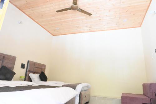 a room with two beds and a ceiling fan at Hotel An Himalayan View in Barkot