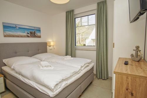 ein Schlafzimmer mit einem großen Bett mit Fenster in der Unterkunft Rex Rugia FeWo12-2 strandnah,Terrasse,Sauna,Pool in Lobbe