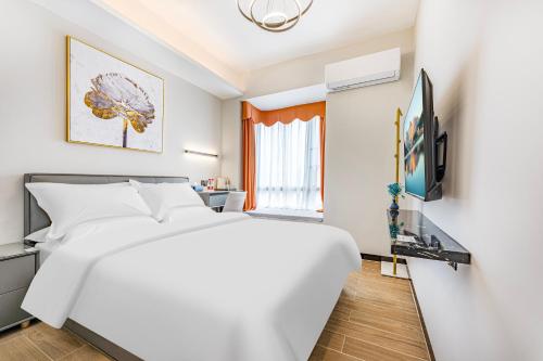a bedroom with a white bed and a television at 漫点 Moodlink Hotel at Taikoo Hui, Sports Center in Guangzhou