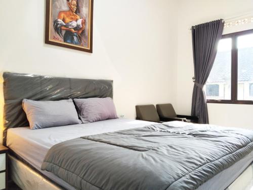 a bedroom with a bed and a painting on the wall at Roemah Kavaleri powered by Cocotel in Bandung