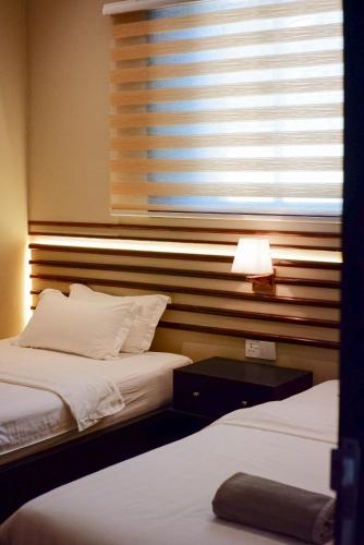 two beds in a hotel room with a window at Bonheur at Karambunai in Kota Kinabalu