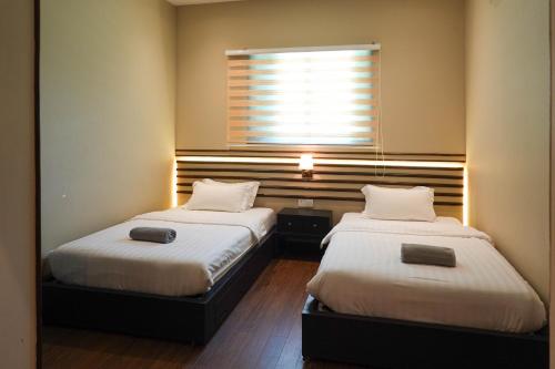 two beds in a small room with a window at Bonheur at Karambunai in Kota Kinabalu