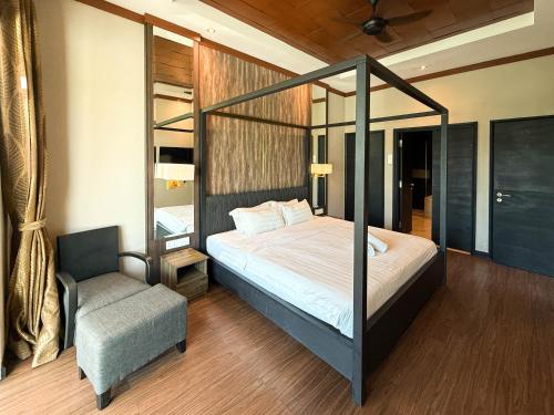 a bedroom with a canopy bed and a chair at Bonheur at Karambunai in Kota Kinabalu