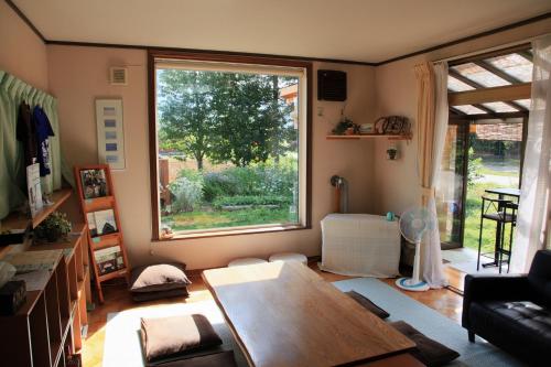 a living room with a table and a large window at Akane-yado in Nakafurano