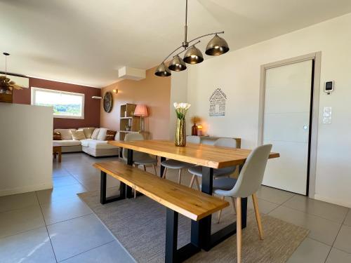 a dining room and living room with a wooden table and chairs at Le temps de vivre in Mormoiron