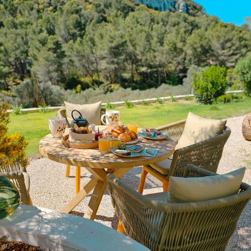 una mesa con un plato de comida con dos sillas en L'hôtel des oiseaux, en Les Baux-de-Provence