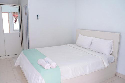 a white bed with two rolled up towels on it at Griya Safitri Syariah in Palembang