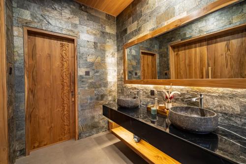 a bathroom with two sinks and a stone wall at Villa Dijabu in Kuta