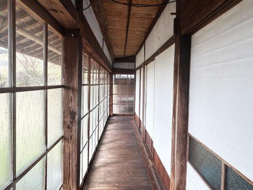 an empty hallway of a building with windows at 古民家一棟貸しナノビレッジ岡山 in Kaga