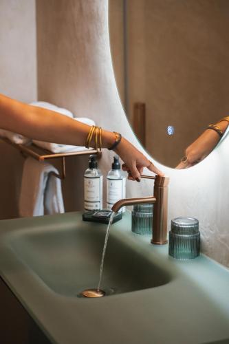 une femme se lave les mains au lavabo d'une salle de bain dans l'établissement Hôtel & Résidence San Roccu, à Saint-Florent