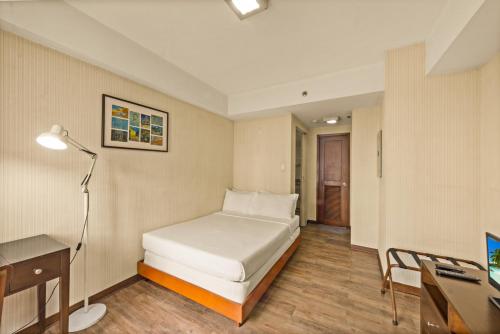 a bedroom with a bed and a desk and a computer at CEO Flats in Manila
