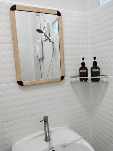 a bathroom with a sink with a mirror and a shower at อามา ภูลังกา เฮาส์ in Ban Sakoen