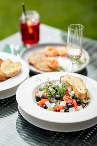 a table topped with plates of food and a salad at Hotel Platan in Gdańsk