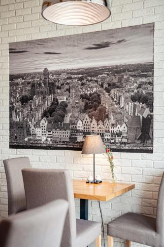 a painting hanging on a wall with a table and chairs at Hotel Platan in Gdańsk