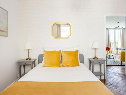 - une chambre avec un lit doté d'oreillers jaunes et d'un miroir dans l'établissement Merveil Family Suite - Tilsitt - Eiffel Tower view, à Paris