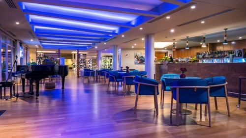 a restaurant with blue tables and chairs and a piano at Hotel Corte Valier in Lazise