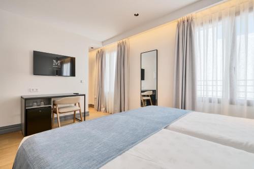 a bedroom with a bed and a desk and a television at Hotel Murillo Reinoso in Seville
