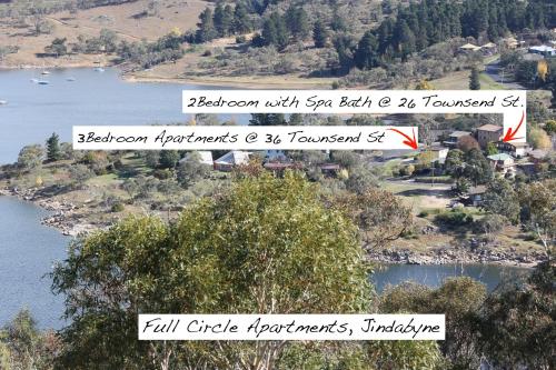 a view of a river with trees and a town at Full Circle Apartments in Jindabyne