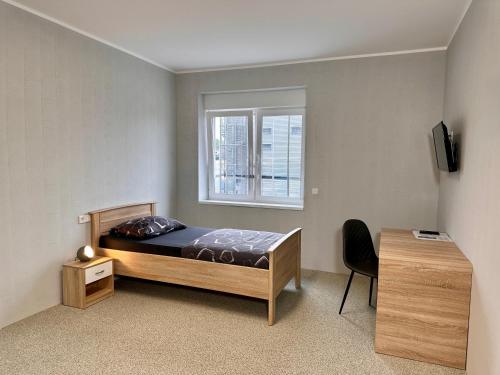 a bedroom with a bed and a window and a desk at GPHotel/Boardinghaus in Leverkusen