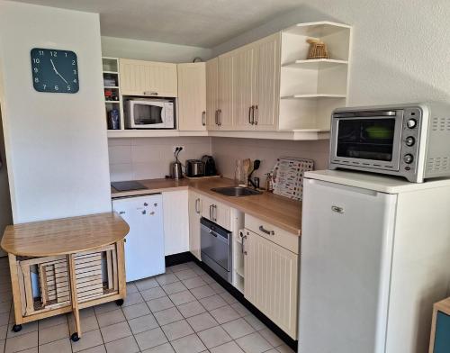 une cuisine avec un réfrigérateur et un micro-ondes dans l'établissement Rare location vacances appartement Banyuls vue mer avec parking, à Banyuls-sur-Mer