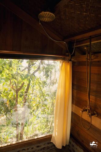 a window with a curtain in a room with a tree at Xieng Retreat in Hanoi