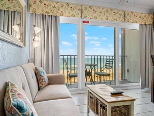 a living room with a couch and a balcony at Southern Comfort - Expansive views of the ocean and beach! Newly renovated plus top grade linens! condo in Carolina Beach