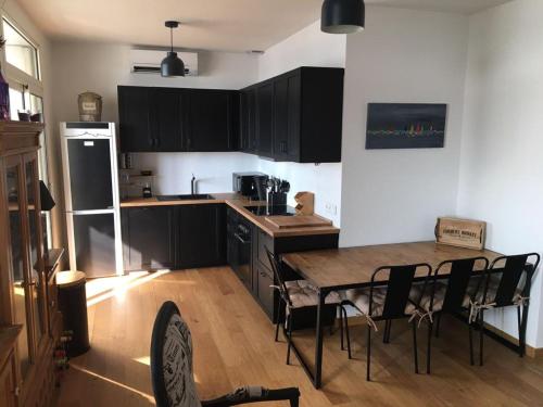 une cuisine avec des armoires noires, une table et des chaises dans l'établissement Appartement vue mer Pointe Rouge, à Marseille