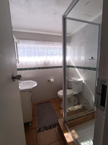 a bathroom with a toilet and a glass shower door at SANTANA 107 Margate in Margate
