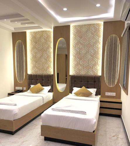 two beds in a hotel room with a mirror at UPTOWN Inn in Bengaluru
