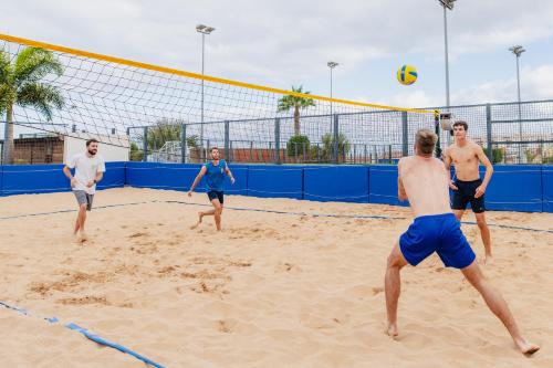 a group of men playing a game of volleyball on a beach at Landmar Costa los Gigantes Family Resort in Puerto de Santiago