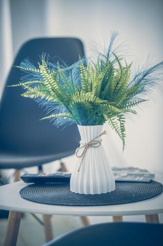 a white vase with a plant in it on a table at Bárka Vendégház Aggtelek in Aggtelek